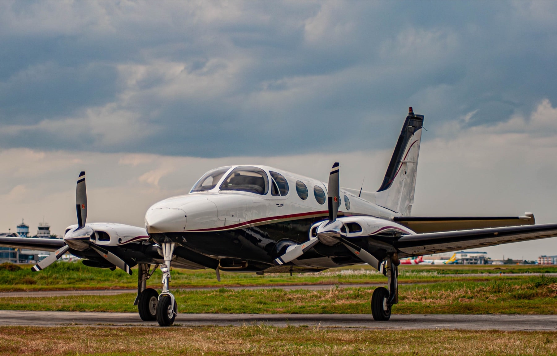 Cessna 340 on MCIA apron at dusk — pressurized twin with cloudy sky backdrop, MCIA control tower in the distance
